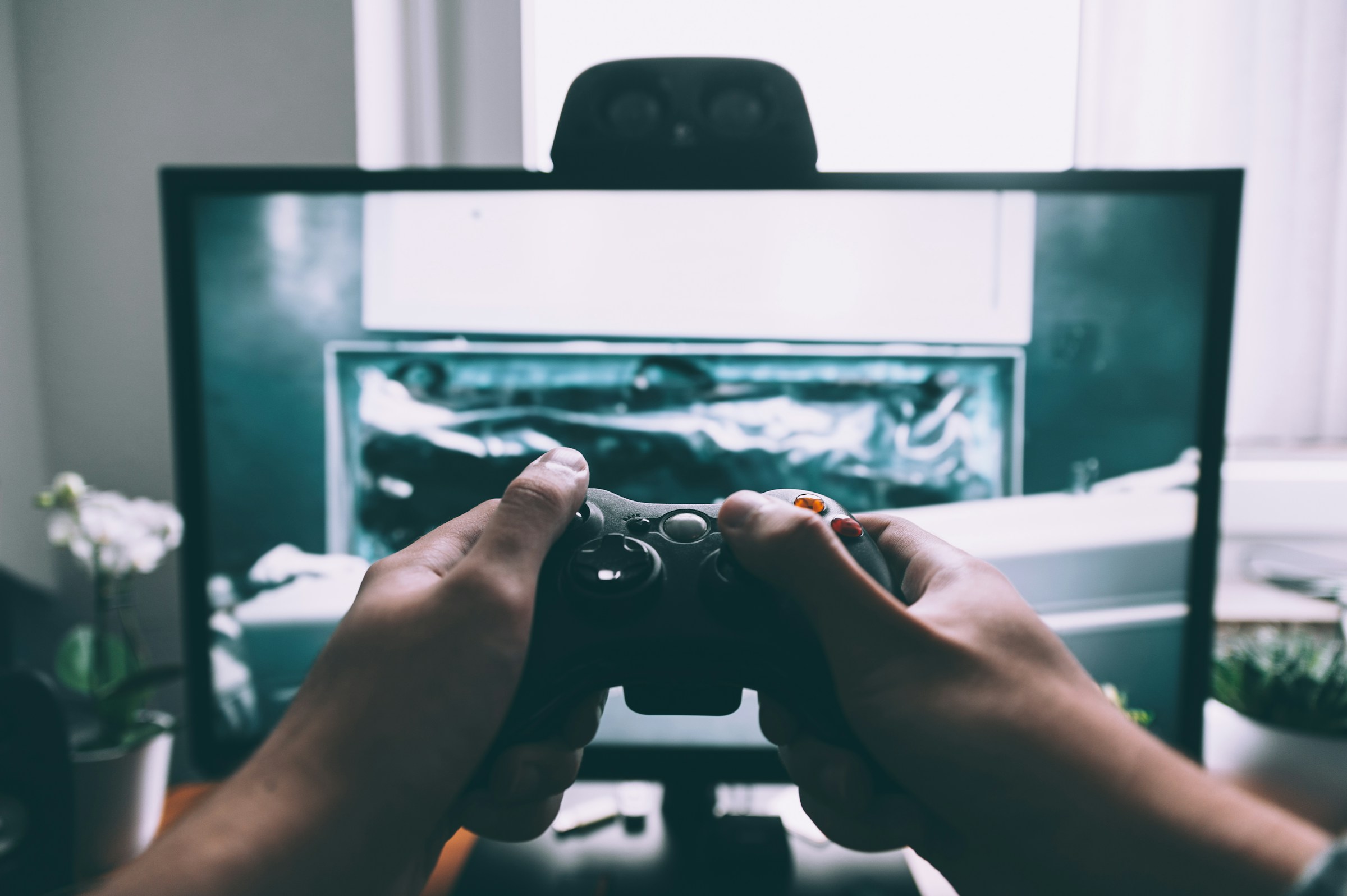 Gaming player and controller A player using a game controller in front of a screen